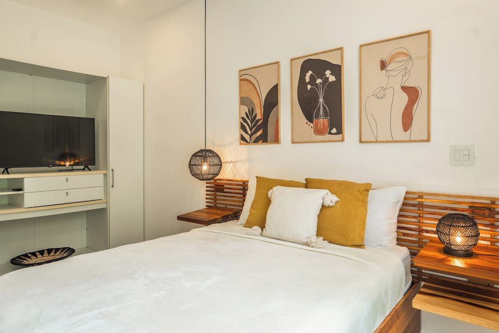 Une chambre à coucher moderne, avec un lit, des tables de chevet, une armoire et des œuvres d’art accrochées au mur.