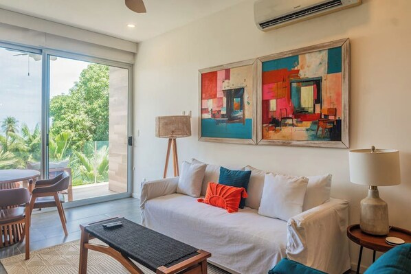 Un salon moderne avec un canapé, une table basse et un tableau accroché au mur.