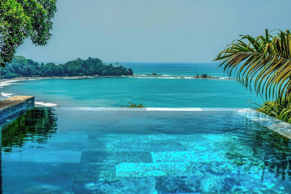 Una piscina infinita con vistas al océano y un paisaje tropical.