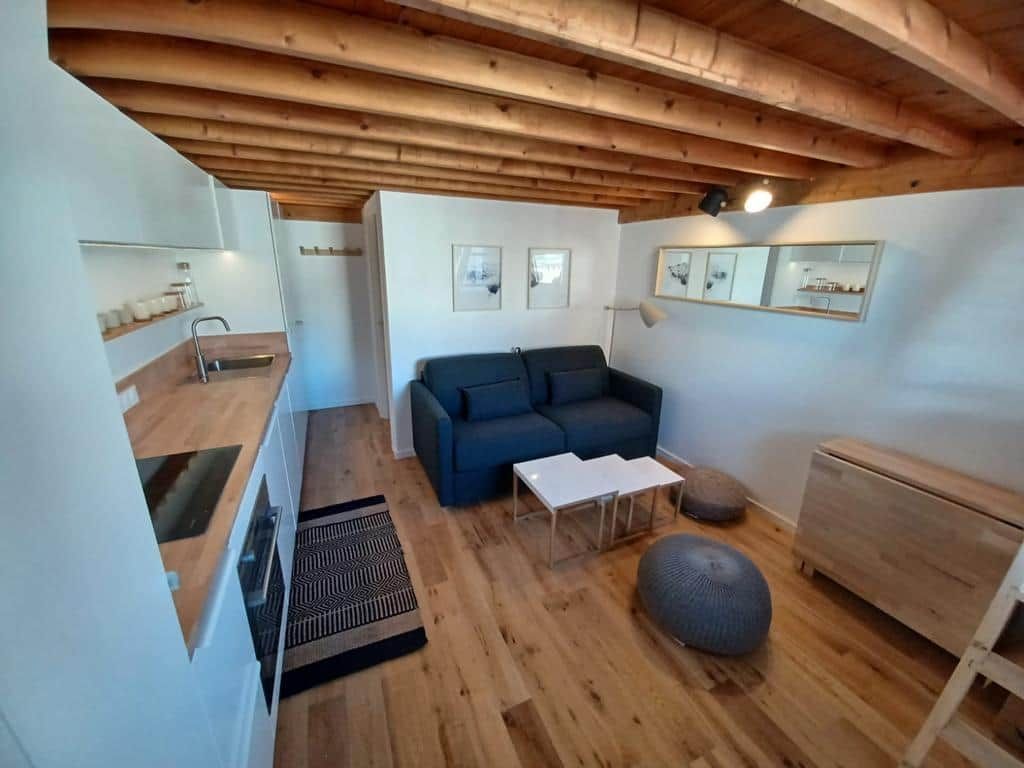 Uma sala de estar moderna com teto de madeira, um sofá, uma mesa de centro e um tapete pequeno.