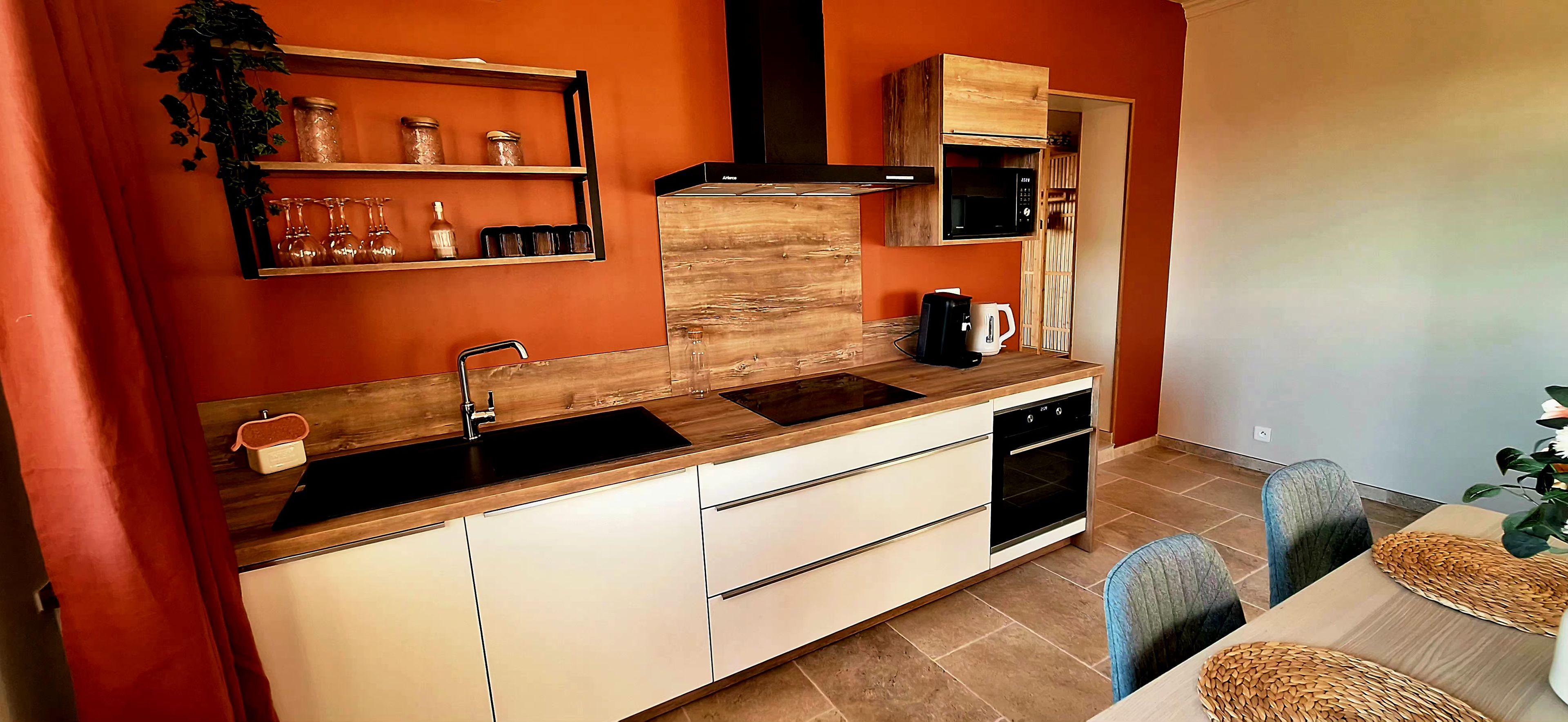 A compact kitchen with a wooden countertop, a built-in oven, and a microwave.