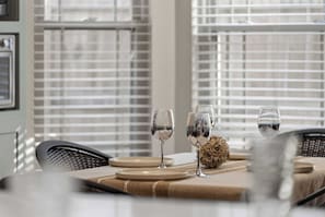 Una mesa de comedor dispuesta con platos, vasos y un objeto decorativo.