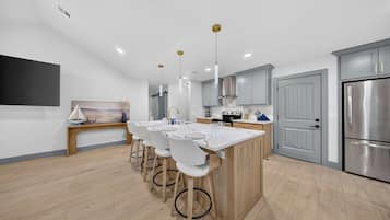 A modern kitchen with a central island, bar stools, and stainless steel appliances.