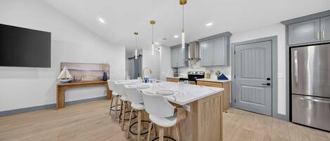 A modern kitchen with a central island, bar stools, and stainless steel appliances.
