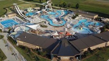 A water park with multiple pools, slides, and a large building with a sloped roof.