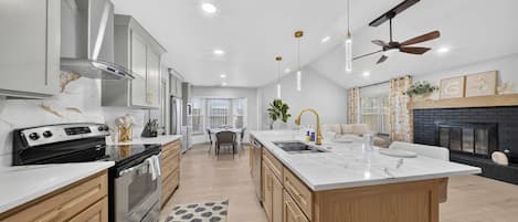 A modern kitchen with a central island, built-in oven, and stainless steel appliances.