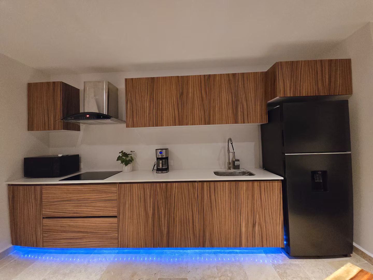 Une cuisine moderne avec des meubles en bois, un réfrigérateur en acier inoxydable et une machine à café.