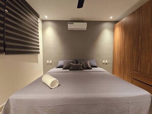 Ein Schlafzimmer mit einem Bett, Kissen, einer Decke, einer Klimaanlage und einem Holzschrank.