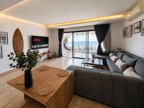 A modern living room with a grey sofa, a wooden coffee table, and a TV displaying Netflix.