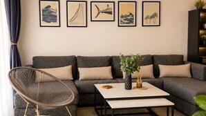 En moderne stue med en modulsofa, en gyngestol, et sofabord og en væg med indrammede kunstværker.