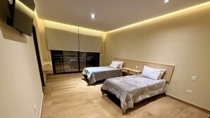 A modern bedroom with two beds, a sliding glass door, and a flat-screen TV mounted on the wall. - Minimalist apartment in the jungle (Puerto Iguazú)