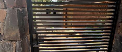 A black metal gate with horizontal slats, set against a stone wall.