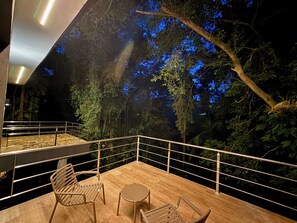 Una terraza al aire libre con barandilla, dos sillas y una mesa pequeña.