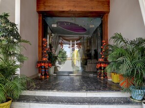 A hotel entrance with a marble floor, potted plants, and traditional decorative elements. - Deluxe Hotel Rk Heights And Banquets (Varanasi)