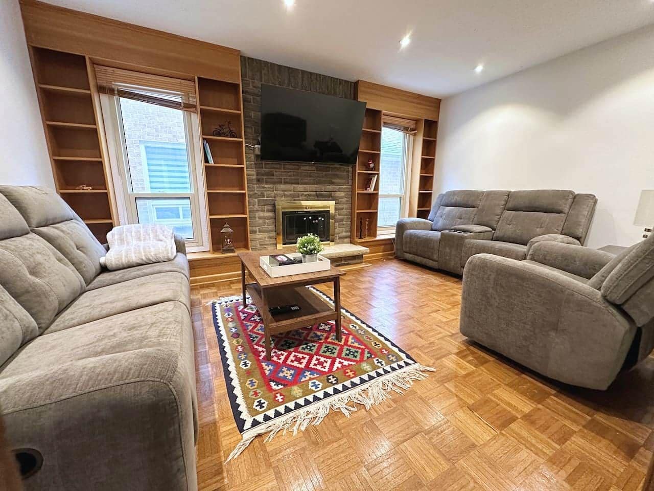 A living room with a fireplace, two sofas, a coffee table, and a TV mounted on the wall.