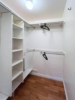 Ein begehbarer Kleiderschrank mit offenen Regalen und einer Kleiderstange.