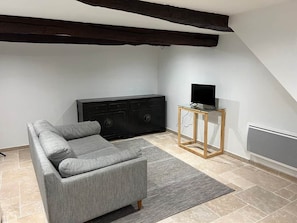 A modern living room with a grey sofa, a black entertainment unit, and a small wooden side table. - Valbonne Village - Rue Giraud (Valbonne)