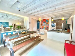 A modern kitchen with a central island, pendant lighting, and a colorful abstract painting on the wall. - by Calamari.Homes - Casa Aura Victoria - Visitors permitted (Cartagena de Indias)