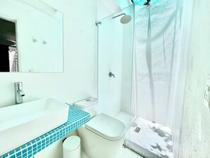 Een badkamer met een witte wastafel, toilet en douchecabine.