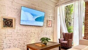 Ein Wohnzimmer mit Backsteinwand, einem Flachbildfernseher, einem Schachbrett, einer Couch und einem Sessel.