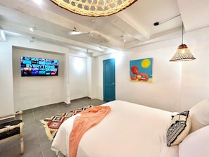 Et moderne hotelværelse med seng, fjernsyn ophængt på væggen, en dør og et maleri.