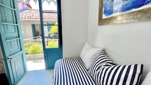 Ein Zimmer mit einem Bett, einem Bild von einem Fisch und Blick auf ein Gebäude mit rotem Dach durch eine offene Tür.