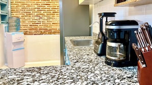 Eine Küche mit Backsteinwand, Wasserspender, Kaffeemaschine und Messerblock.