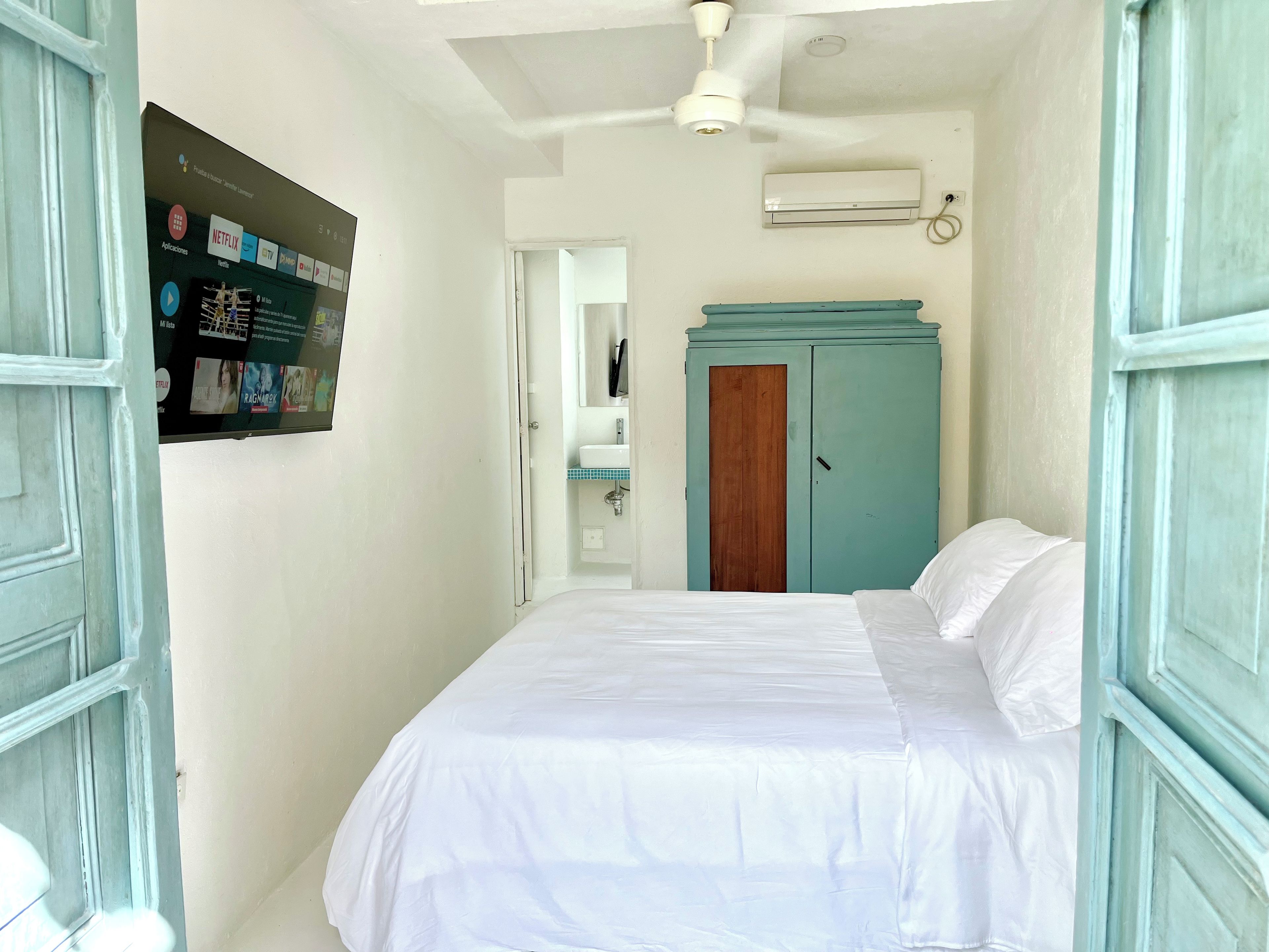 Un dormitorio con cama, armario, ventilador de techo y unidad de aire acondicionado.