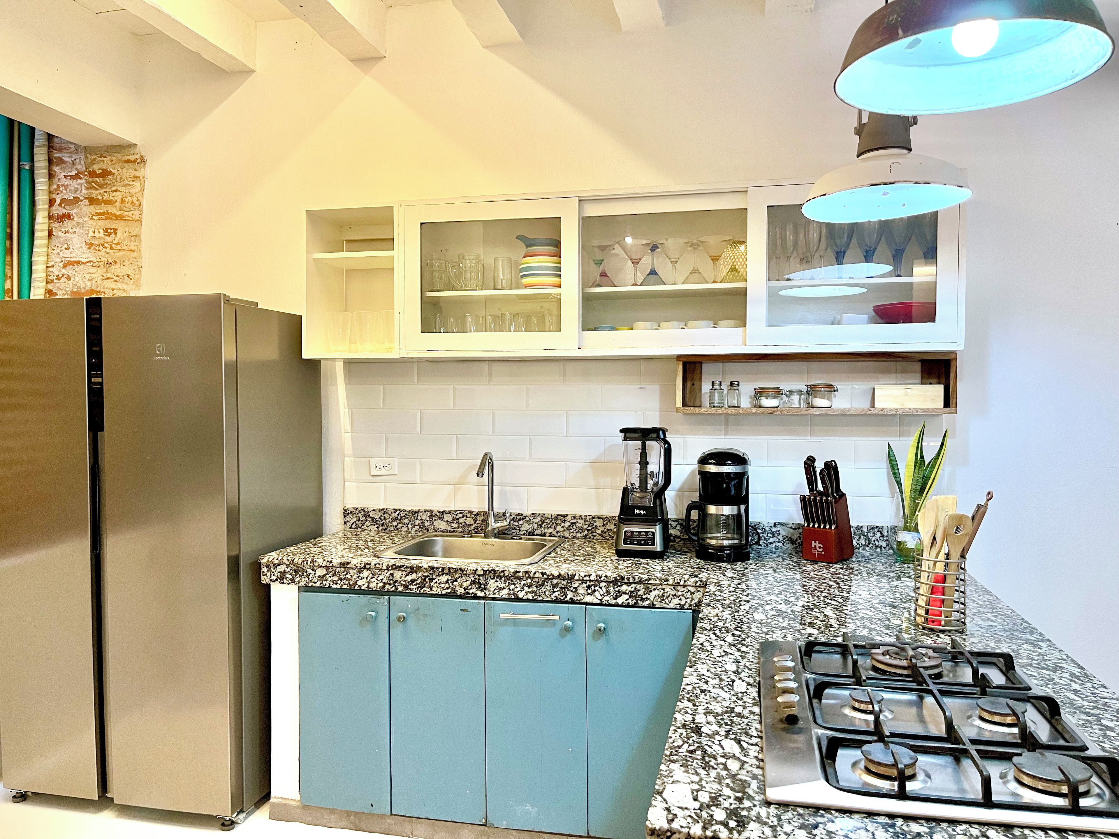 A kitchen with a stainless steel refrigerator, a gas stove, a coffee maker, and a sink.