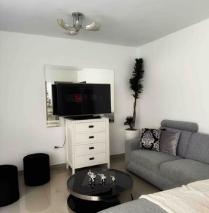 A modern living room with a flat-screen TV, a white cabinet, a grey sofa, a round coffee table, and a ceiling fan. - Fully Furnished Apartment in Miraflores (Miraflores)