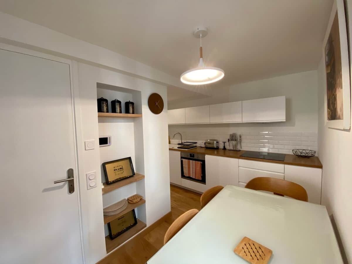 A compact kitchen with white cabinets, a wooden countertop, and a hanging light fixture.