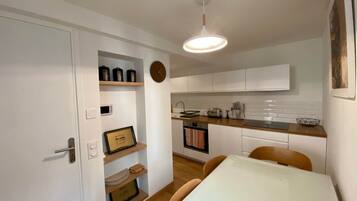 A compact kitchen with white cabinets, a wooden countertop, and a hanging light fixture.