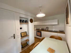 Una cucina compatta con mobili bianchi, un piano di lavoro in legno e un lampadario.