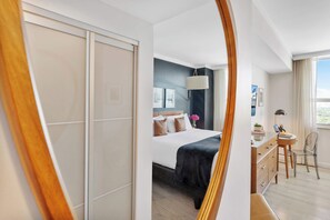 Et hotelværelse med seng, natbord, lampe og udsigt over byen.