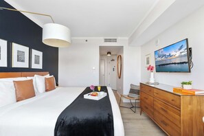 Ein Hotelzimmer mit einem Bett, einem Schminktisch, einem Fernseher und gerahmten Bildern an der Wand.