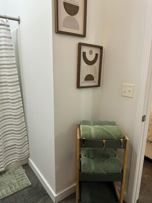 A bathroom with a towel rack, a framed abstract artwork, and a green towel rack with towels. - "Beautiful Luxury Loft in the Heart of Downtown" (Memphis)