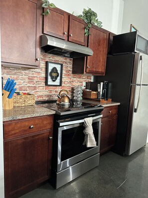 A kitchen with wooden cabinets, a stainless steel oven, a microwave, and a refrigerator. - "Beautiful Luxury Loft in the Heart of Downtown" (Memphis)
