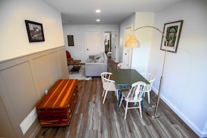 A compact living space with a dining area, a sofa, a bench, and a lamp. - Gameday Large Group Central 1 Mile From Stadium - Space for 16-19 (State College)