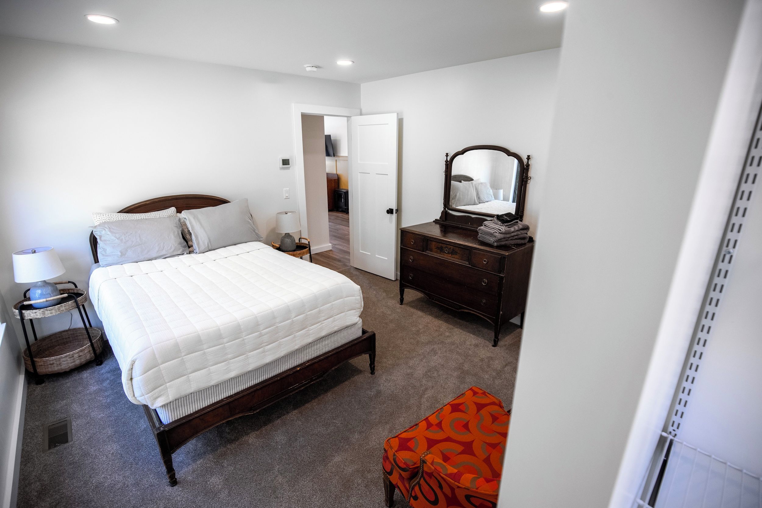 Een slaapkamer met een bed, een dressoir en een spiegel.