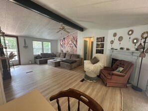 A spacious living room with a fireplace, a ceiling fan, and a large window. - Scenic Waterfront 1 Acre Home w/dock, kayaks, paddleboard, wifi and raised deck. (La Crosse)