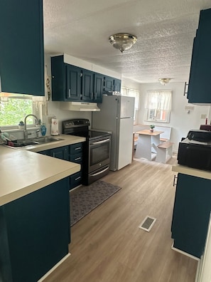 A compact kitchen with dark cabinets, a stove, and a refrigerator. - Scenic Waterfront 1 Acre Home w/dock, kayaks, paddleboard, wifi and raised deck. (La Crosse)