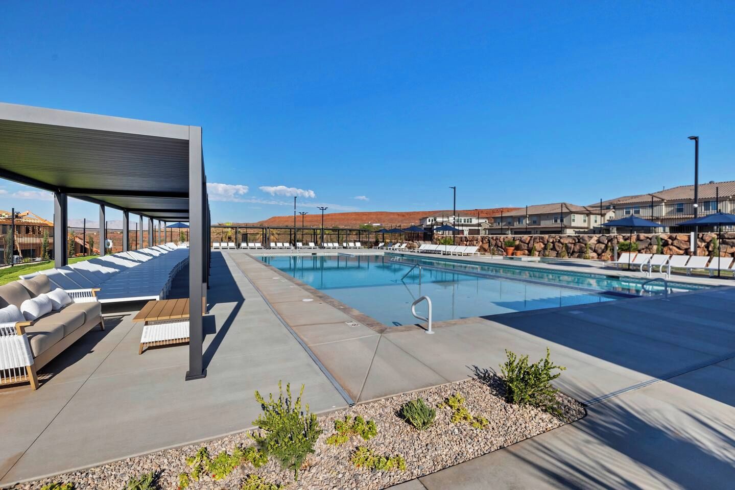 A swimming pool with lounge chairs and a covered seating area.