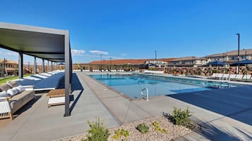 A swimming pool with lounge chairs and a covered seating area.