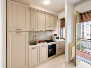 A kitchen with light wood cabinets, a marble backsplash, a black stove, a sink, and a window with blinds. - Casa Mimosa - One Bedroom Apartment, Sleeps 5 (Marina di Andora)