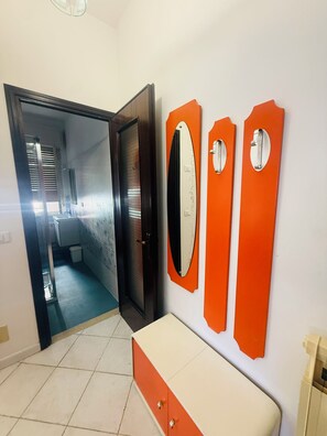 A bathroom with a toilet, a sink, and a mirror. There is a door leading to another room. - Casa Mimosa - One Bedroom Apartment, Sleeps 5 (Marina di Andora)