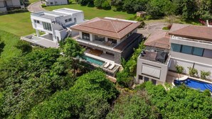 Un barrio residencial con casas modernas, una piscina y vistas al mar.