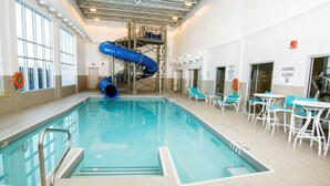 Ein Hallenbad mit blauer Rutsche, Liegestühlen und einem Rettungsschwimmerstandort.