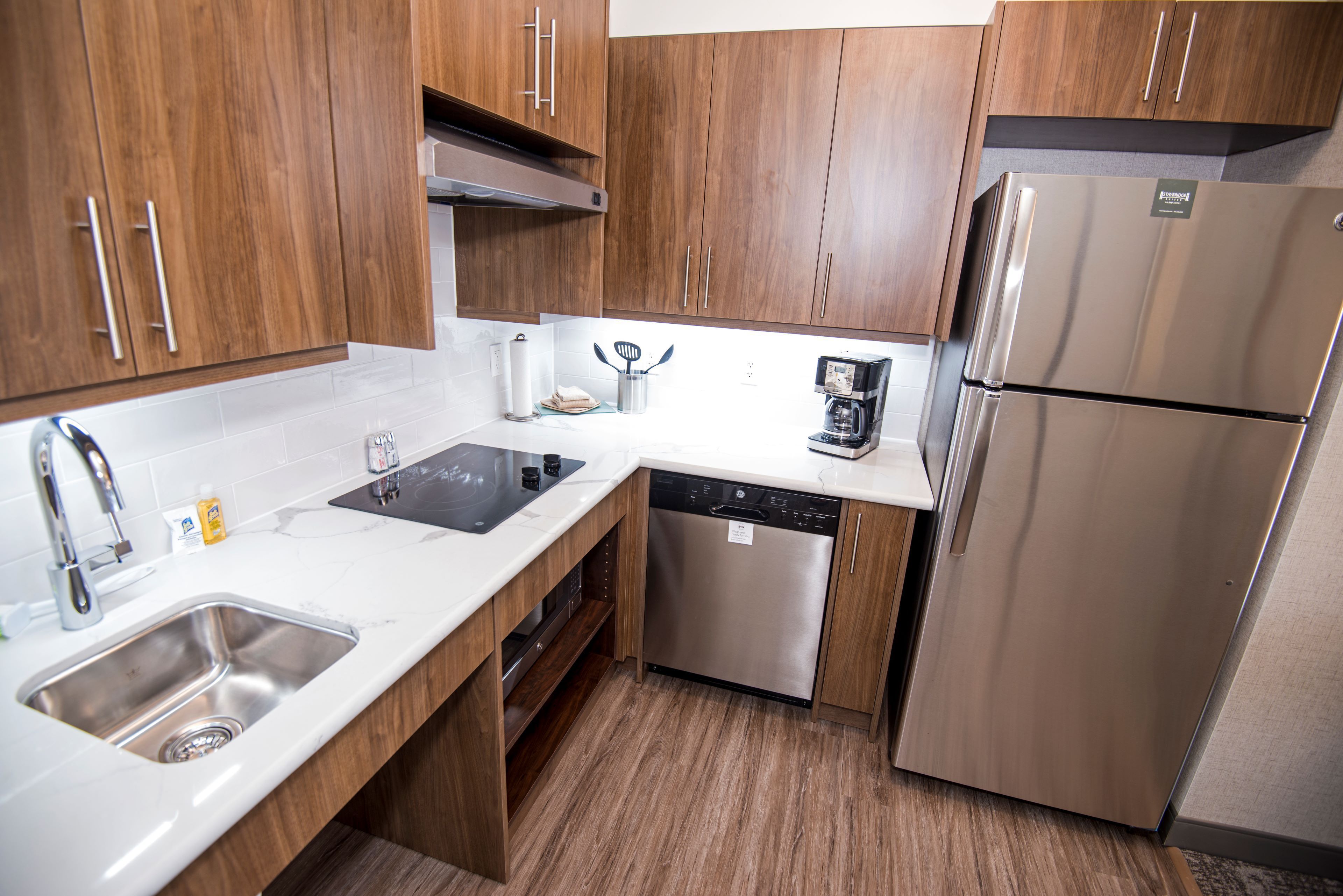Een moderne keuken met roestvrijstalen apparatuur, houten kastjes en een vaatwasser.