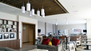 Eine moderne Hotelhalle mit Sitzgelegenheit, einer Rezeption und einer Küchenzeile im Hintergrund.