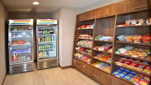 Ein Verkaufsautomatenbereich mit Snacks und Getränken, darunter ein Kühlschrank und ein Regal mit verschiedenen Produkten.